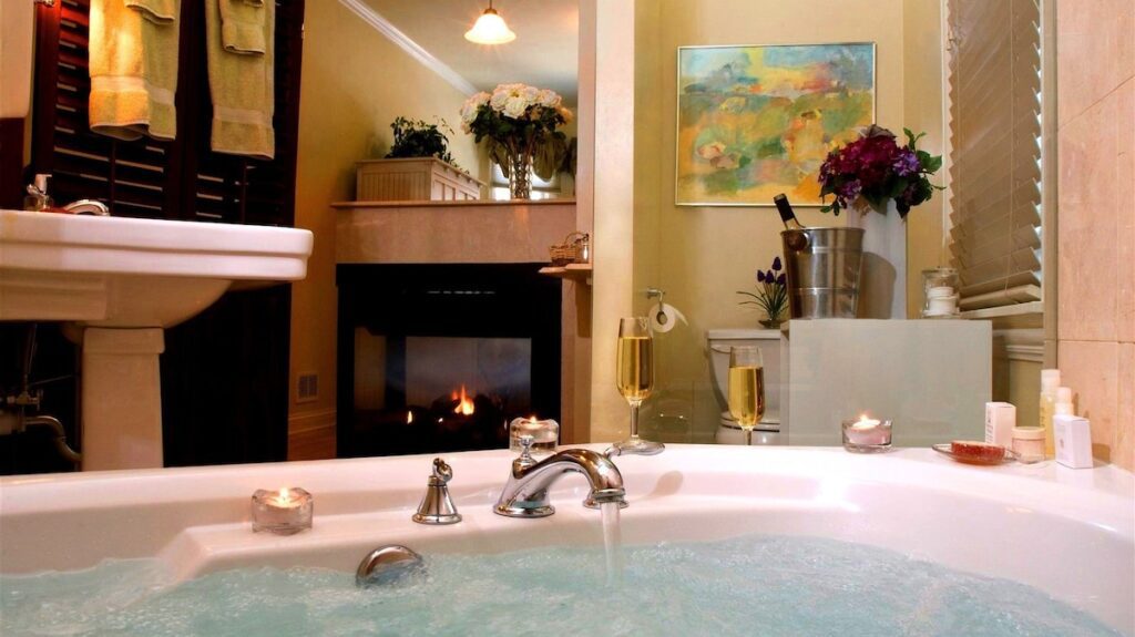 Romantic bathroom with bubbling Jacuzzi tub, candles, champagne glasses, and fireplace in cozy bed and breakfast